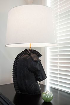 a black horse head lamp sitting on top of a table next to a green apple