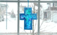 a blue cross hanging on a window sill