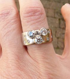 a person's hand with a ring on it that has three stones in the middle