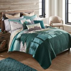 a bed covered in a blue and green comforter next to a wooden headboard