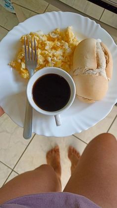 a person is holding a plate with food on it and a cup of coffee in front of them