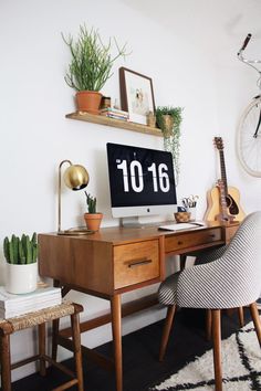 a desk with a clock and some plants on it