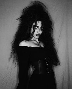 black and white photograph of a woman with long hair wearing a corset in front of a wall