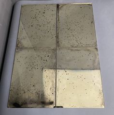 four square silver tiles with black spots on them