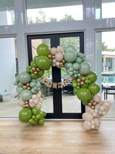 a wreath made out of balloons sitting on top of a wooden table in front of a glass door