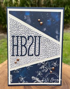 a card with the letter hb2u on it, sitting on top of a tree stump