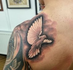 a man with a tattoo on his back has a bird flying in the sky above him