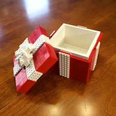 an open red and white box sitting on top of a wooden table next to a lego model