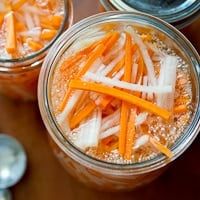 two jars filled with food sitting on top of a wooden table next to spoons