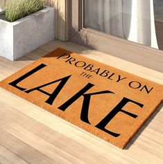 a door mat that says probably on the lake next to a potted grass plant