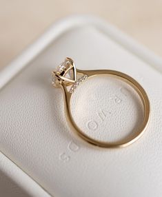 an engagement ring sitting on top of a white box