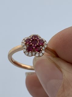 a person holding up a ring with red and white stones in it's center