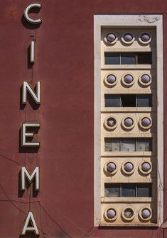 a red building with the word cinema on it's side and round holes in the window