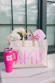 a pink and white bag sitting on top of a table next to a vase with flowers