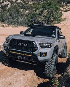 a gray toyota truck driving down a dirt road