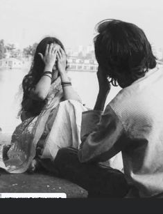 black and white photograph of two people sitting next to each other with their hands covering their eyes