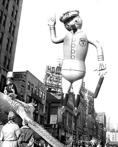 an inflatable balloon is being carried down the street as people watch from below