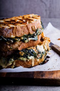 two grilled cheese sandwiches stacked on top of each other next to a cutting board