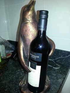 a bottle of wine sitting on top of a counter next to a statue of a penguin