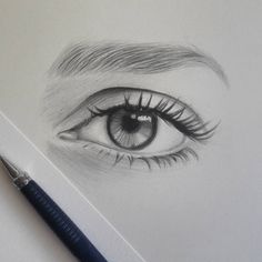 a pencil drawing of an eye with long lashes on paper next to a marker pen