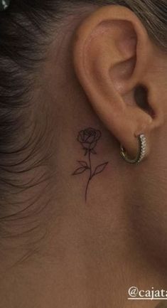 a woman's ear with a small rose tattoo on it