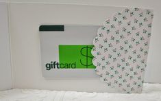 the gift card is placed on top of the white box with green and red designs