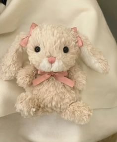 a stuffed rabbit with a pink bow on it's head sitting on a blanket