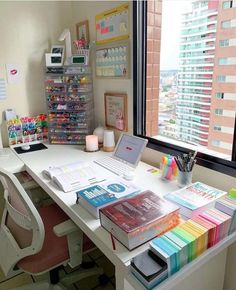 a white desk topped with lots of books next to a window