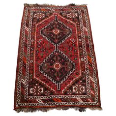 an antique persian rug with red and black designs on the bottom, fringes around the edges