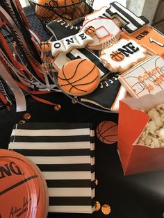 an assortment of sports themed cookies and snacks on a table with basketballs, candy sticks, and paper plates