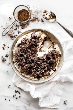 a pie is sitting on a plate with chocolate shavings and spoons next to it