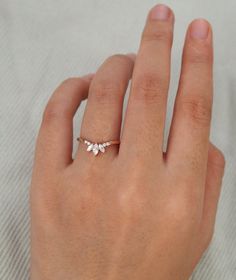 a woman's hand wearing a gold ring with three small white flowers on it