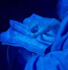 a close up of a person reading a book with blue light coming from behind them