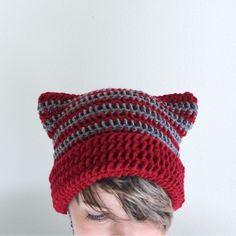 a woman wearing a red and gray knitted cat hat