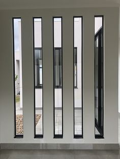 four windows in a white building with black frames on the wall and concrete flooring