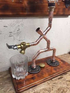 a glass and some metal pipes on a wooden stand next to a wall mounted clock