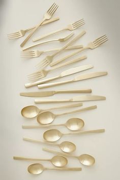 spoons and forks arranged in the shape of a pyramid on a white surface,