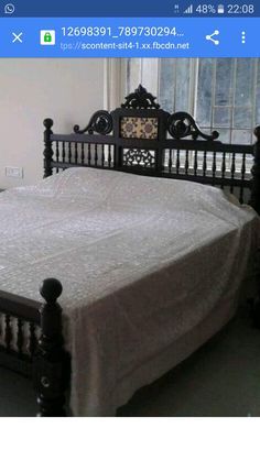 a bed with white sheets and black headboard in a room next to a window