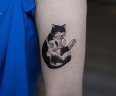 a black and white cat sitting on top of a person's arm