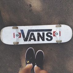 a person standing next to a skateboard with the word vans on it's side