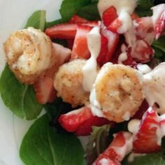 a salad with shrimp, strawberries and dressing on it