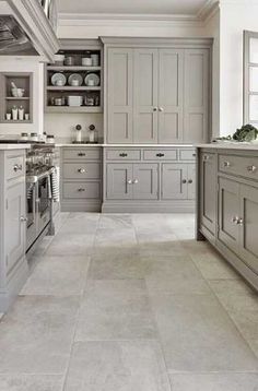 a large kitchen with gray cabinets and white counter tops, along with marble flooring