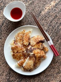 some food on a white plate with chopsticks and a cup of tea next to it