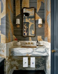 a bathroom with marble counter tops and gold accents on the walls, along with two lamps