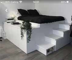 a bed that is on top of some steps in a room with white walls and wood floors