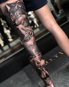 a man's arm with tattoos on it and an image of a wolf in the background