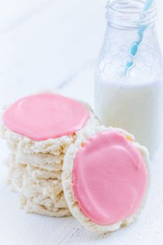 cookies with pink frosting next to a bottle of milk