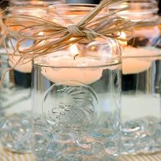 some candles are in glass jars on a table