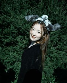 a woman with long hair wearing a black shirt and white bunny ears on her head