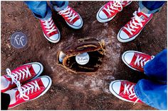 four people standing in the dirt with their feet on a baseball glove and ball mitt